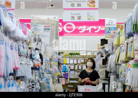 A woman shopping at Daiso 100 Yen Store while wearing a face mask