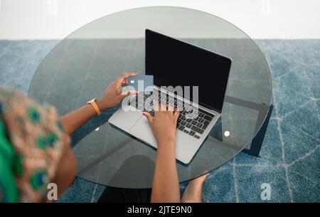 High angle view shot above of Black African woman making an online purchase, shopping using laptop and credit card. Doing digital banking verification Stock Photo