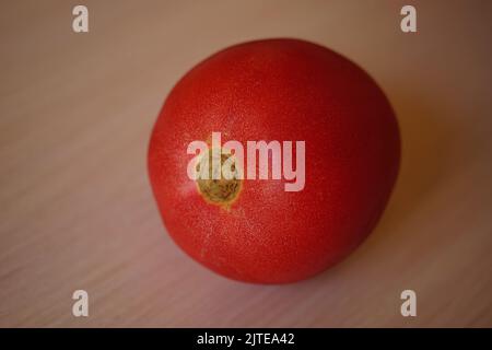 Ripe red tomato on pale wooden table. Stock Photo