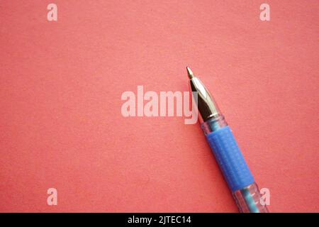 Blue ballpoint pen on red paper. Stock Photo
