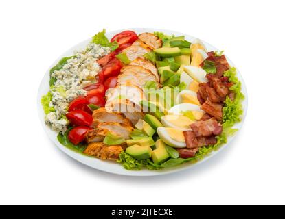 Cobb salad of romain lettuce, slices bacon, avocado, chicken, tomato, eggs, blue cheese, in a white salad bowl isolated on white background. Stock Photo