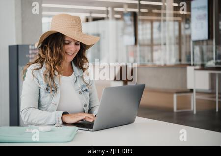 Happy woman using laptop in airport terminal Stock Photo