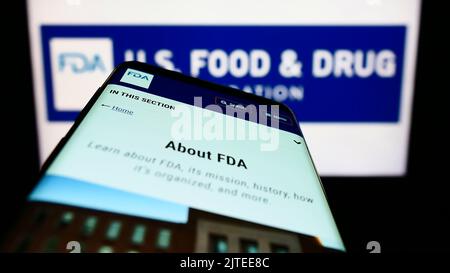 Smartphone with webpage of United States Food and Drug Administration (FDA) on screen in front of logo. Focus on top-left of phone display. Stock Photo