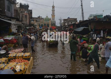 Lahore, Pakistan. 29th Aug, 2022. Pakistani people on their way and busy in Badami bagh vegetable market during heavy monsoon rainfall in Lahore. Fourt spell of monsoon rain has broken a 20-year record as the provincial capital received 248mm of downfall in Eight hours. At least Five persons dead and many injured after two roof and walls collapse and other incidents in provincial capital city Lahore. (Photo by Rana Sajid Hussain/Pacific Press) Credit: Pacific Press Media Production Corp./Alamy Live News Stock Photo