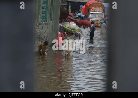 Lahore, Pakistan. 29th Aug, 2022. Pakistani people on their way and busy in Badami bagh vegetable market during heavy monsoon rainfall in Lahore. Fourt spell of monsoon rain has broken a 20-year record as the provincial capital received 248mm of downfall in Eight hours. At least Five persons dead and many injured after two roof and walls collapse and other incidents in provincial capital city Lahore. (Photo by Rana Sajid Hussain/Pacific Press) Credit: Pacific Press Media Production Corp./Alamy Live News Stock Photo