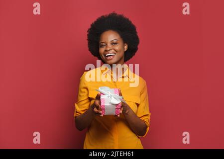 Nice black woman taking pink present gift box, studio portrait Stock Photo
