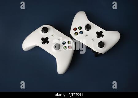 Two gaming gamepads side by side in the center on an isolated dark blue background Stock Photo