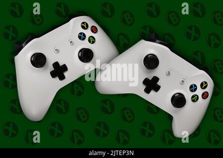 Two gaming gamepads in flight on a dark green background with buttons for games Stock Photo