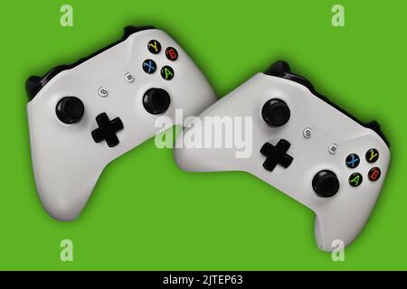 Two gaming gamepads in flight on an isolated green background Stock Photo