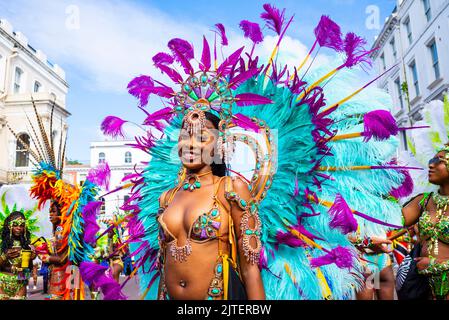 Notting Hill Carnival Grand Parade, on August Bank Holiday Monday 2022 in London, UK. Female wearing large feather plumage outfit. Colourful Stock Photo