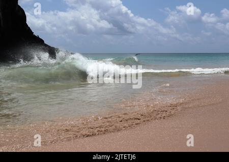 Perfect waves in cristaline waters beside Two Brothers Cliff, Cacimba beach, Fernando de Noronha island, Brazil Stock Photo