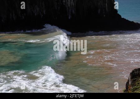 Perfect waves in cristaline waters beside Two Brothers Cliff, Cacimba beach, Fernando de Noronha island, Brazil Stock Photo