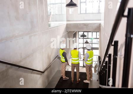 architects in helmets with blueprints at office Stock Photo