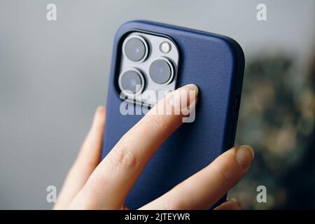 Person holds an iPhone 13 pro in a blue case. Stock Photo