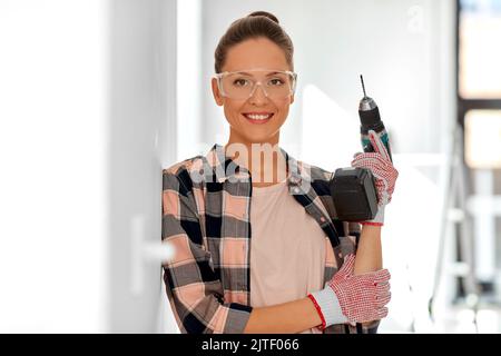 woman in goggles with perforator at home Stock Photo