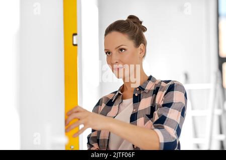woman with level measuring wall at home Stock Photo