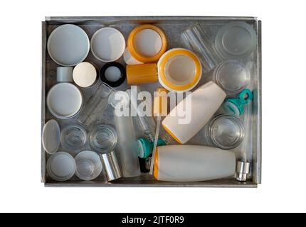 Used glass and plastic cosmetic container jars ready to recycle in stainless steel tray isolated on white background with clipping path. Recycle waste Stock Photo