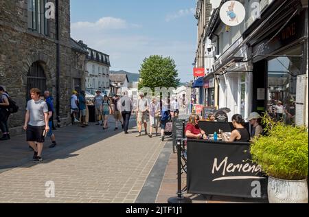 People tourists visitors walkers in the town centre and shops stores cafe in summer Market Square Keswick Cumbria Lake district England UK Britain Stock Photo