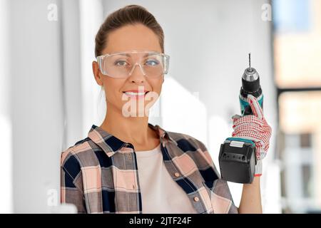 woman in goggles with perforator at home Stock Photo