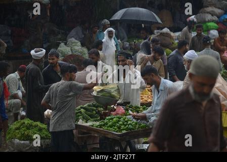 Lahore, Pakistan. 29th Aug, 2022. Pakistani people on their way and busy in Badami bagh vegetable market during heavy monsoon rainfall in Lahore, Pakistan on August 29, 2022. The monsoon rain has broken a 20-year record as the provincial capital received 248mm of downfall in Eight hours. At least Five people are dead and many injured after two roof and walls collapse and other incidents in provincial capital city Lahore. (Photo by Rana Sajid Hussain/Pacific Press/Sipa USA) Credit: Sipa USA/Alamy Live News Stock Photo