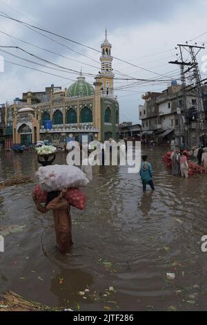 Lahore, Pakistan. 29th Aug, 2022. Pakistani people on their way and busy in Badami bagh vegetable market during heavy monsoon rainfall in Lahore, Pakistan on August 29, 2022. The monsoon rain has broken a 20-year record as the provincial capital received 248mm of downfall in Eight hours. At least Five people are dead and many injured after two roof and walls collapse and other incidents in provincial capital city Lahore. (Photo by Rana Sajid Hussain/Pacific Press/Sipa USA) Credit: Sipa USA/Alamy Live News Stock Photo