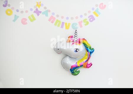 Happy birthday in french and Inflatable unicorn birthday decoration Stock Photo