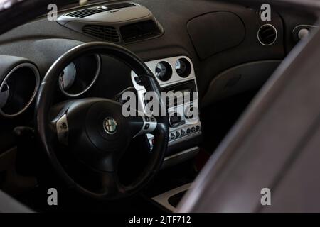 Milan, Italy 30 august 2022: Alfa romeo 156 car interior. Improved black steering wheel with red stitiching, completely black interior. Stock Photo