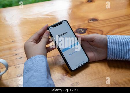 CHIANG MAI, THAILAND - AUG 22 2022: A woman holds Apple iPhone 6s with Instagram application on the screen at cafe. Instagram is a photo-sharing app Stock Photo