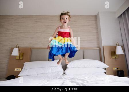 Smiling girl (4-5) jumping on bed Stock Photo