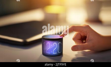 close up of hand with time on smart speaker Stock Photo