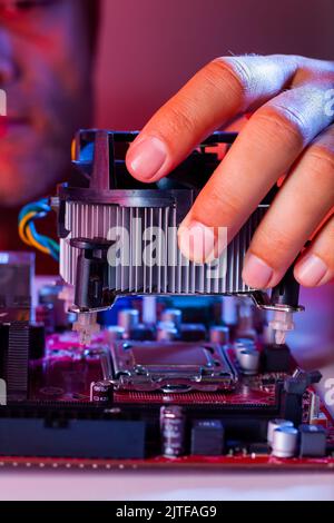 A man's hand inserts a cooler into the motherboard socket. Stock Photo