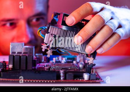 A man's hand inserts a cooler into the motherboard socket, close-up Stock Photo