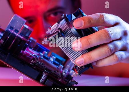 A man's hand inserts a cooler into the motherboard socket, close-up Stock Photo