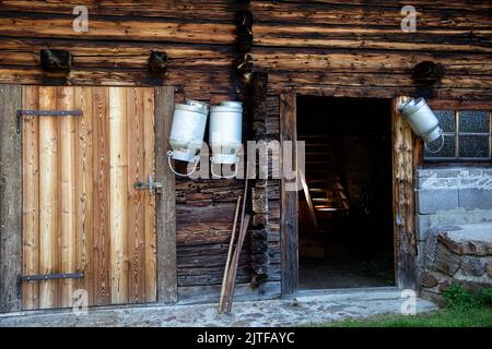 Milk pots hanging on stable wall, mountain village Oberstalleralm, Innervillgraten, Tyrol, Austria Stock Photo