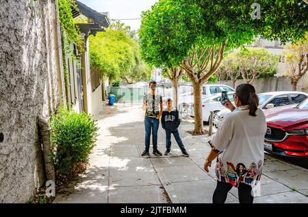 A lady takes a photograph of her two sons using her mobile phone while on holiday in San Francisco, California, USA Stock Photo