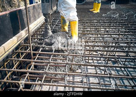 Construction workers are pouring concrete to formwork Stock Photo