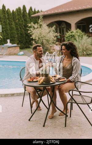 Handsome young couple sitting in the backyard, drinking lemande and eating fresh fruits Stock Photo