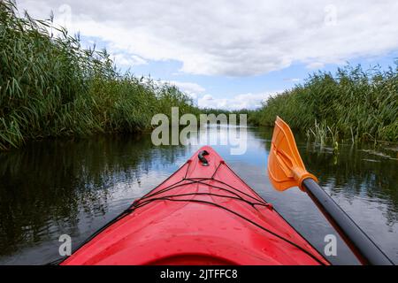 Kayaker point of view. Kayak bow with a view on the river and rushes.   River kayaking concept. Active vacations in wild nature. Stock Photo