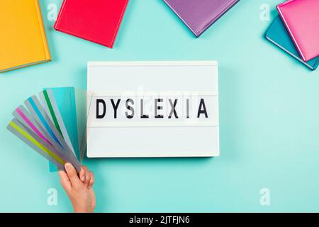 Dyslexia awareness, help children with reading, learning difficulties concept. Lightbox with DYSLEXIA word and kid hand holding reading highlight Stock Photo