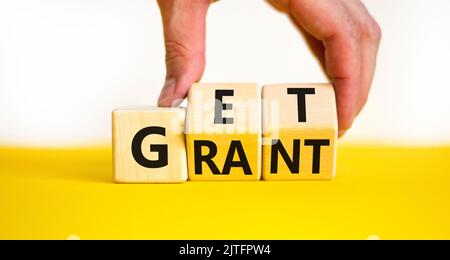 Get grant symbol. Businessman turns wooden cubes with concept words Get grant on a beautiful yellow table white background. Copy space. Business and g Stock Photo