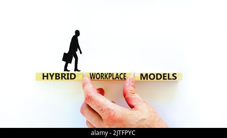 Hybrid workplace models symbol. Concept words Hybrid workplace models on wooden blocks. Businessman hand. Beautiful white background. Business hybrid Stock Photo