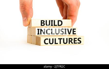 Build inclusive cultures symbol. Concept words Build inclusive cultures on wooden blocks. Businessman hand. Beautiful white background. Business build Stock Photo