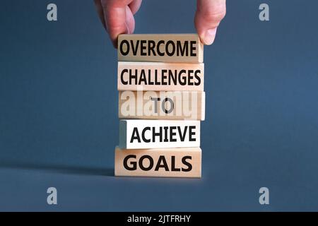 Overcome challenges to achieve goals symbol. Concept words Overcome challenges to achieve goals on wooden blocks on a beautiful grey background. Busin Stock Photo