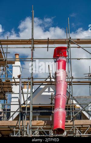 rubble chute attached to some scaffolding on a house renovation, waste building materials chute on some scaffolding on a building being repaired. Stock Photo