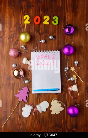 New Year 2023 words written in an office notebook. Concept in business. Plans for the new year. Flat lay. Wooden background. Vertical photo Stock Photo