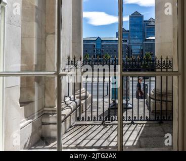 The Ulster Bank Headquarters on Georges Quay in Dublin, Ireland viewed through a window of the Customs House  on Custom House Quay. Stock Photo
