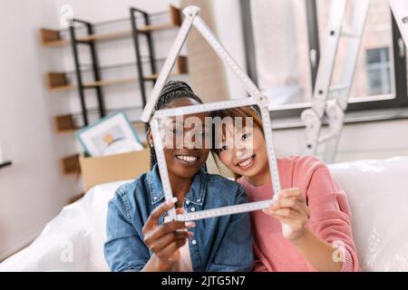 happy smiling women with ruler in shape of house Stock Photo