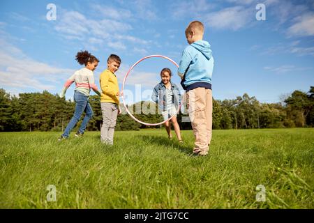 happy children playing game with hula hoop at park Stock Photo