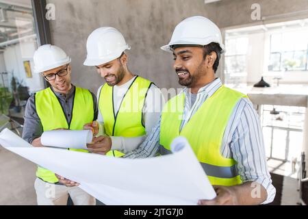 architects in helmets with blueprint at office Stock Photo