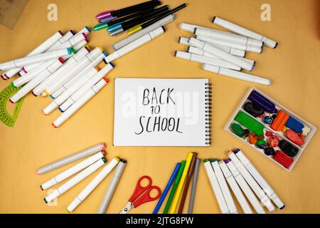 Many different office supplies. School markers, pens and plasticine. Inscription on notebook back to school Stock Photo